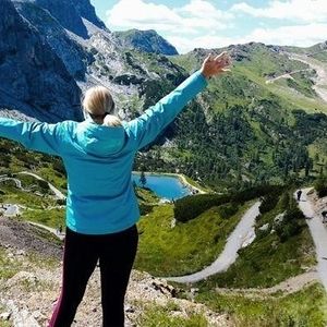 Eine Frau mit blauer Jacke steht vor Bergen