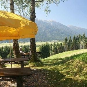 Eine Sitzbank mit Sonnenschirm steht in einer Landschaft