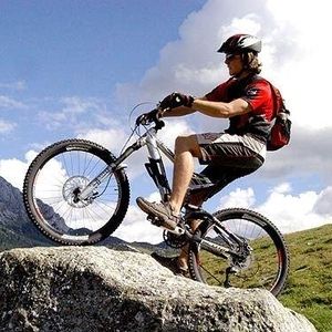Ein Mann sitzt auf einem Fahrrad und steht auf einem Hügel