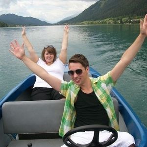 Zwei Leute sitzen in einem Boot und halten die Hände in die Luft