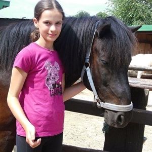 Ein Mädchen steht vor einem braunen Pony