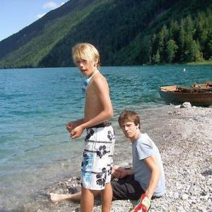 Two boys sitting in front of blue water